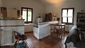 Una cocina compacta con una isla central, armarios de madera y un comedor con mesa y sillas.