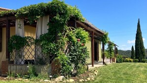 Una casa con porche cubierto, cimientos de ladrillo y césped bien cuidado.