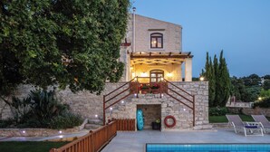A stone building with a pool, wooden deck, and a staircase leading to a balcony. - Stone Made villa in picturesque village! Private pool & full privacy! (Rethymno)