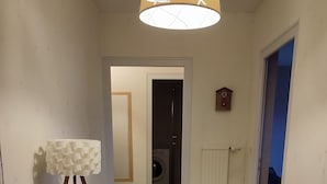 Un couloir avec une table, un lave-linge et un radiateur.