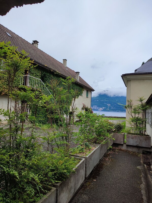 A residential area with a house featuring a balcony and a view of a lake and mountains.