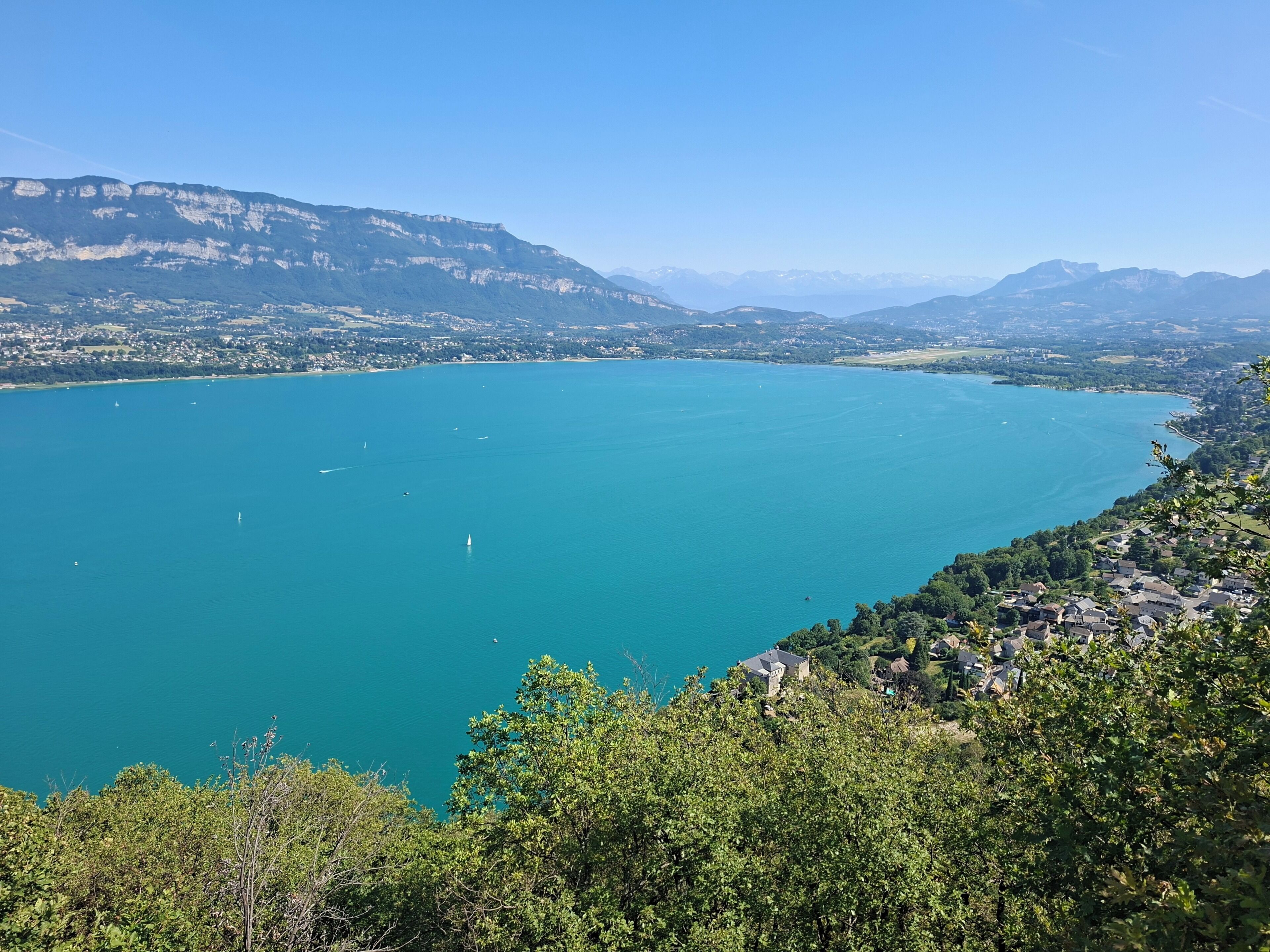 Une vue panoramique d’un lac entouré de montagnes et d’un quartier résidentiel.