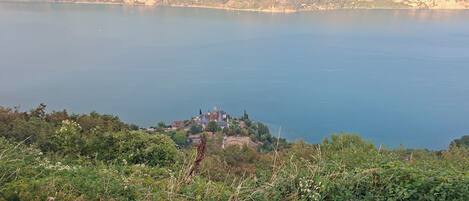 Un paisaje costero con una masa de agua, un pequeño poblado con edificios y un fondo montañoso.