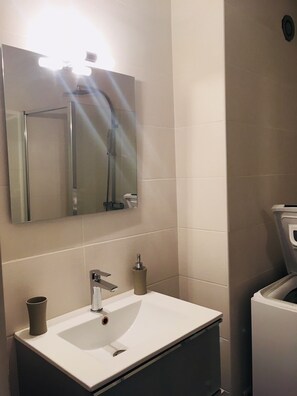 Een badkamer met een wit wastafel, een spiegel en een douche.