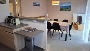 Une cuisine moderne équipée d’une machine à café, d’une poubelle et d’un coin repas avec une table et des chaises.