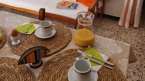 Una sala de estar acogedora con sofá, una mesita de centro y un comedor con individuales, platos y una jarra de jugo de naranja.