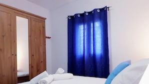 Un dormitorio con cama, un armario de madera y una cortina azul.