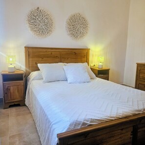Une chambre à coucher avec une tête de lit en bois, deux tables de chevet avec des lampes et un lit recouvert de linge de lit blanc.