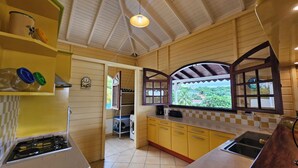 Una cocina pequeña con armarios amarillos, una estufa a gas y un ventanal de diseño arqueado.