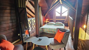 Um quarto de cabana de madeira aconchegante, com uma cama, uma mesinha e duas cadeiras.