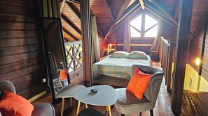 Ein gemütliches Schlafzimmer einer Holzhütte mit einem Bett, einem kleinen Tisch und zwei Stühlen.
