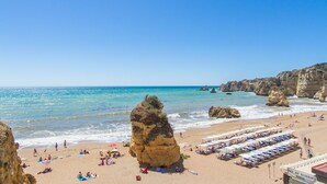 Une plage caractérisée par une formation rocheuse imposante, un rivage sablonneux et un restaurant-bar proposant des collations.
