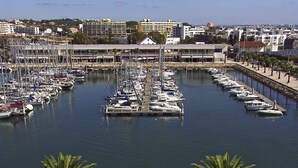 Un port de plaisance où de nombreux bateaux sont amarrés dans une baie tranquille, entourée de bâtiments et de palmiers.