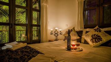 A well-lit bedroom with a bed, a bedside table with a candle, and a window with curtains.