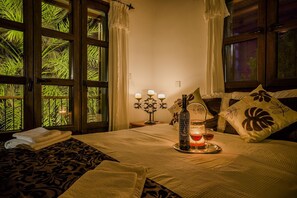 Een goed verlichte slaapkamer met een bed, een nachtkastje met een kaars, en een raam met gordijnen.