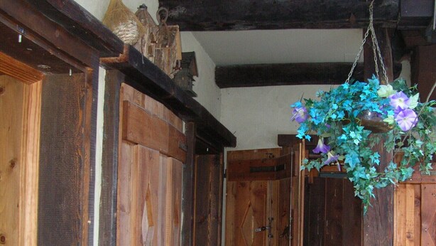 Un intérieur rustique avec des éléments en bois, notamment un banc en bois, une corbeille à fleurs suspendue et des armoires en bois.