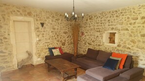 Ein Wohnzimmer mit Steinwand, Couch, Couchtisch aus Holz und einer Pendelleuchte.