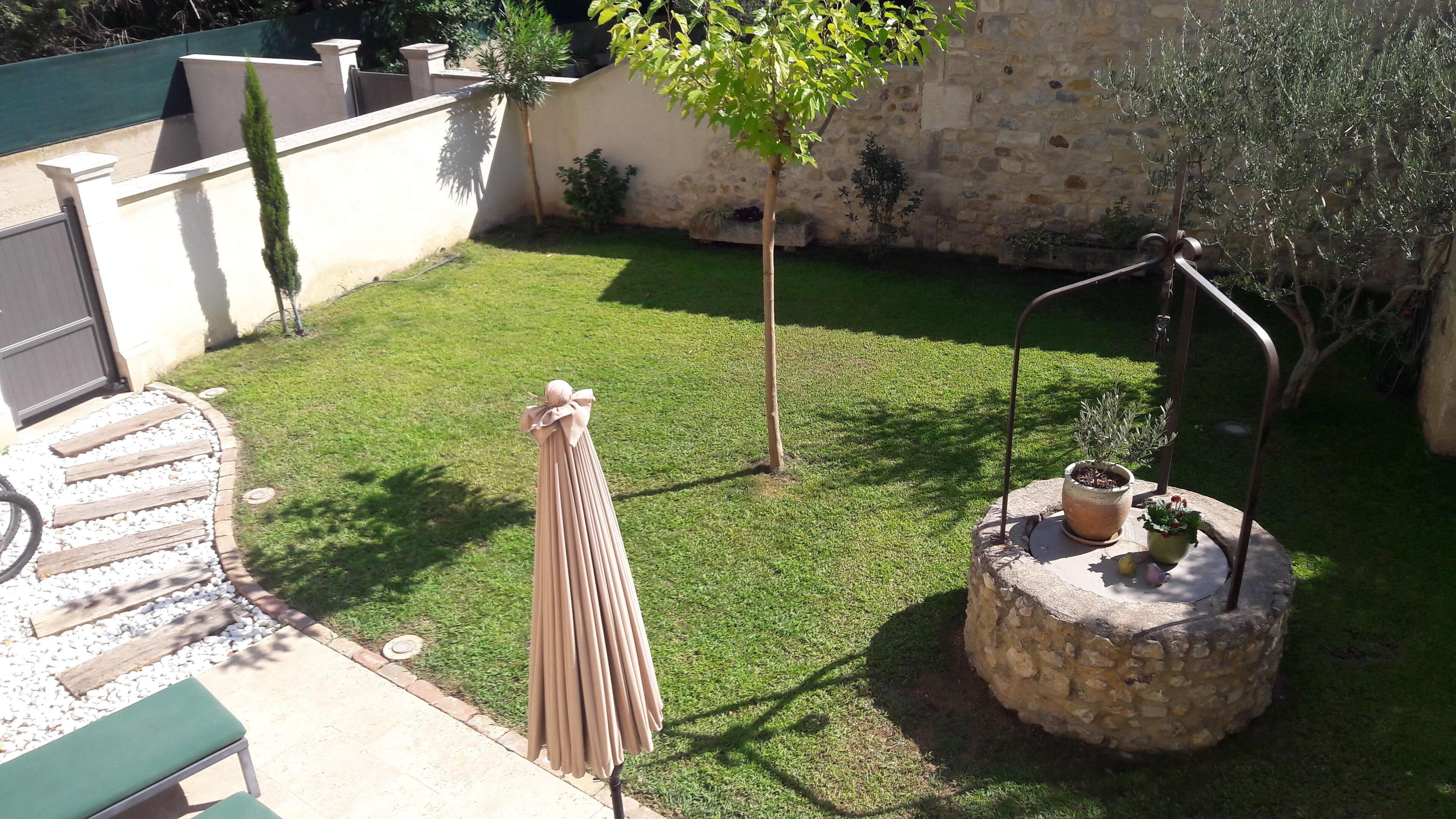 Um jardim bem cuidado com uma fonte de pedra, um banco de madeira e uma pequena árvore.