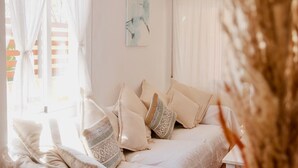 Una camera accogliente con un letto, cuscini e un quadro appeso al muro.