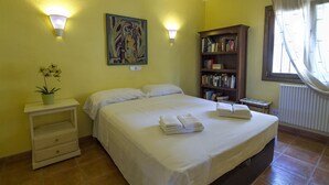 A bedroom with a bed, bedside tables, a bookshelf, and a window with curtains.