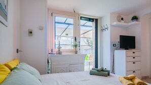 A bedroom with a bed, a TV, a desk, and a window. - Sea View 2bed Apartment overlooking the Gulf with Private Terrace (Napoli)