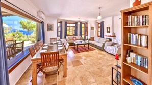 Un amplio salón con un ventanal grande, un conjunto de sofás, una mesa de centro y una estantería.