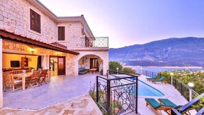 Un edificio de piedra con un patio, una piscina y vistas al mar.
