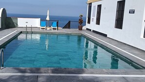 A rectangular swimming pool with a metal ladder on one side, surrounded by a tiled deck. - Tenerife, La Arena Beach 300 m away, free Wi-Fi, community pool (Santiago del Teide)