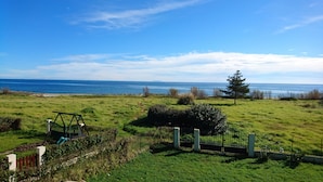 A grassy field with a swing set, a tree, and a view of the ocean. - 70m from the beach, pretty house 200m2, sea view, 6 bedrooms, 5 bathrooms, 7 wc, enclosed garden, 15 people (Poggio-Mezzana)