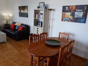 A living room with a wooden dining table, a black leather sofa, and a bookshelf. - "Excellent Relaxing and peaceful". Villa with Private Solar heated Pool (Playa Blanca)