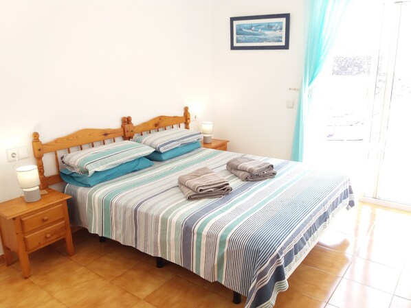 A neatly made bed with striped bedding, two bedside lamps, and a small wooden nightstand. - "Excellent Relaxing and peaceful". Villa with Private Solar heated Pool (Playa Blanca)
