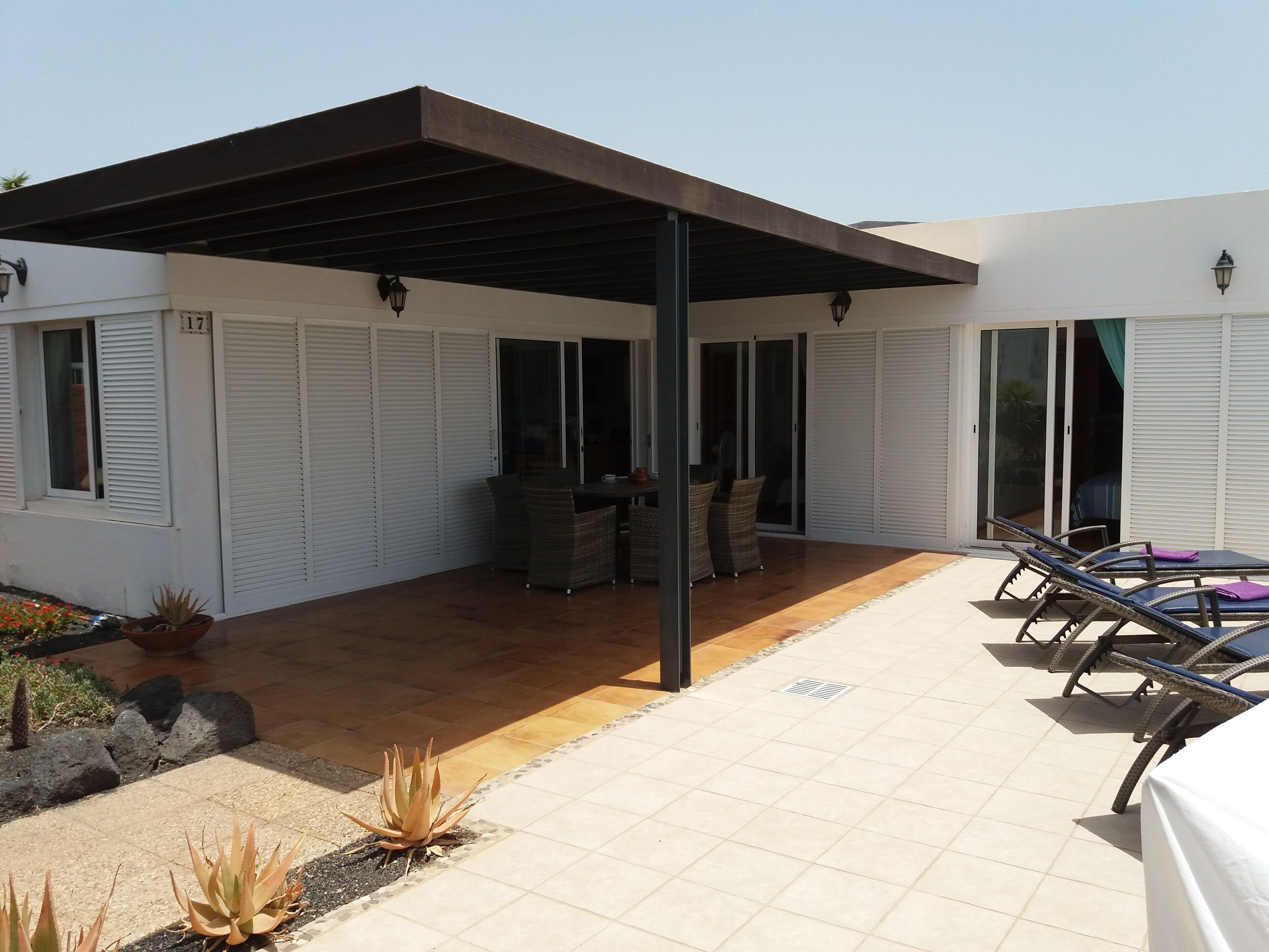 Ein überdachter Patio-Bereich mit Gartenmöbeln und einer Pergola.