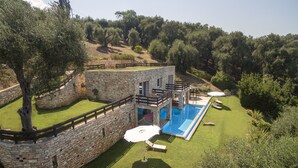 Un edificio de paredes de piedra con piscina, mobiliario exterior y un césped bien cuidado.