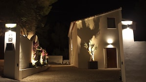 Un bâtiment moderne et bien éclairé, doté d’une entrée sécurisée par un portail, d’un petit jardin agrémenté de plantes à fleurs et d’un chemin menant à l’entrée principale.