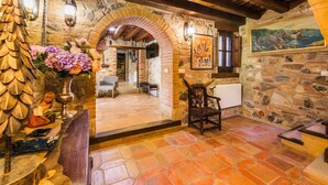 A rustic interior with stone walls, a wooden ceiling, and a tiled floor.