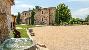 A courtyard with a stone building, a fountain, and a well-maintained lawn.