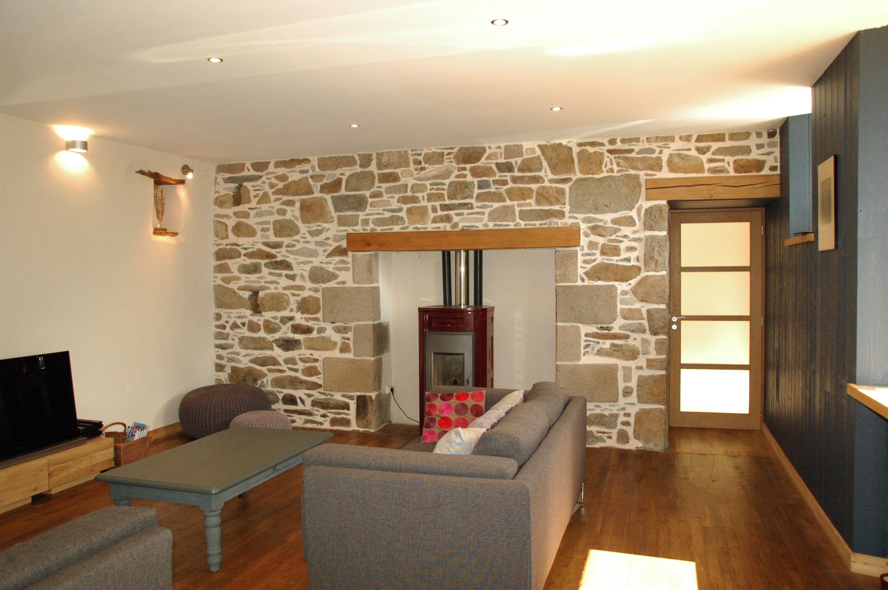 A living room with a stone wall, a fireplace, a sofa, a coffee table, and a television.