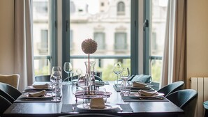 Een eettafel voor vier personen, met uitzicht op een gebouw door grote ramen.