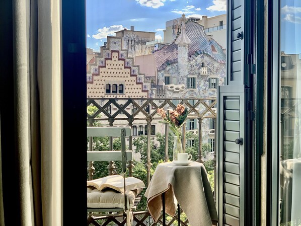 A balcony with a view of a building with colorful facades and a table with a vase of flowers.