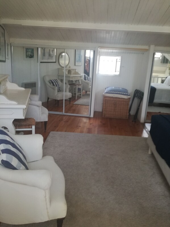 A cozy living room with a white sofa, a small table, and a mirror. There is a sliding door leading to a dining area with a table and chairs. - Air-Conditioned Cottage With Pool in Vence. (Vence)
