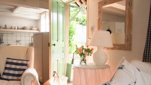 A cozy room with a white sofa, a striped pillow, a lamp on a small table, and a mirror on the wall. - Air-Conditioned Cottage With Pool in Vence. (Vence)