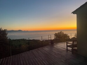 A wooden deck with a railing overlooking a body of water and distant landforms. - House / Villa - LES ISSAMBRES (Roquebrune-Sur-Argens)