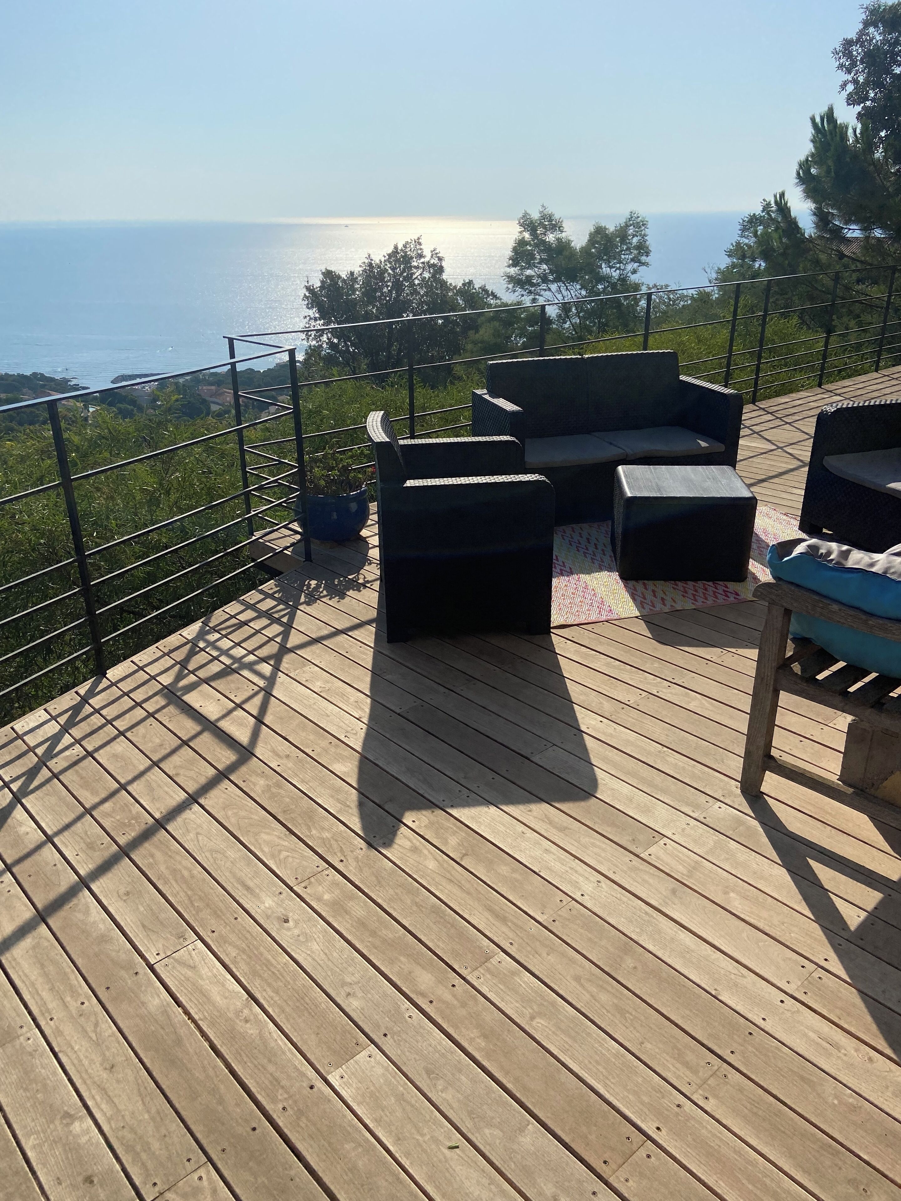 A wooden deck with outdoor furniture, including sofas and a table, overlooking a body of water.