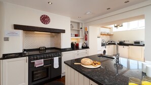 Een moderne keuken met een centraal eiland, een ingebouwde oven en een klok aan de muur.