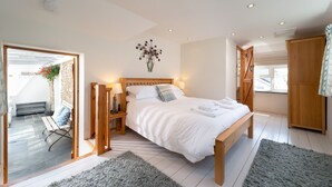 Een slaapkamer met een houten bed, nachtkastjes, een groot raam en uitzicht op buiten.