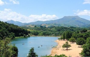 Un riu amb barques, una platja sorrenca i un paisatge de muntanyes al fons.