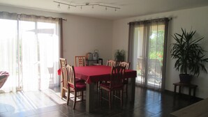 A dining area with a red table, wooden chairs, a potted plant, and a sliding glass door leading to a balcony. - House / Villa - Saint Pée sur Nivelle (Saint-Pée-Sur-Nivelle)