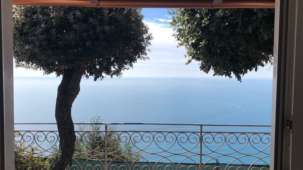 A view from a covered balcony with a metal railing, overlooking a body of water. - confortable cottage with stunning seaview and total privacy in the nature (Montemarcello-Ameglia (SP))