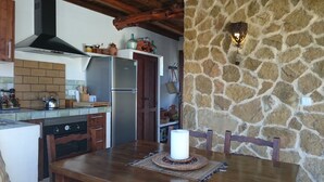 A kitchen with a stone wall, a refrigerator, a stove, and wooden cabinets.