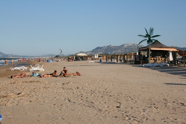 A beach with people sunbathing, umbrellas, and beach chairs.